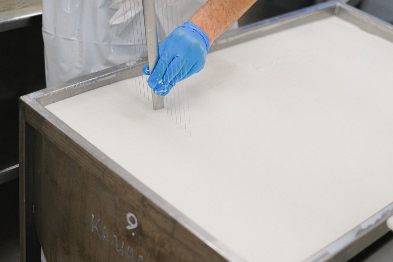 Trabalhador utiliza uma ferramenta durante a produção de queijo em uma unidade de laticínios.